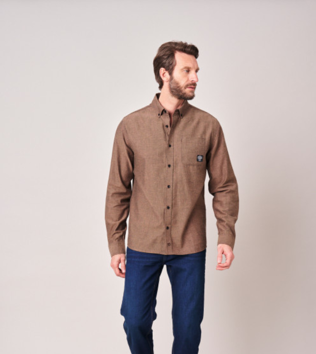 Homme portant une chemise marron à manches longues et un pantalon bleu
