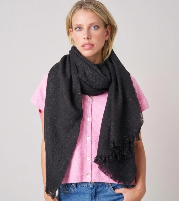 Écharpe noire à franges pour femme portée avec un gilet rose