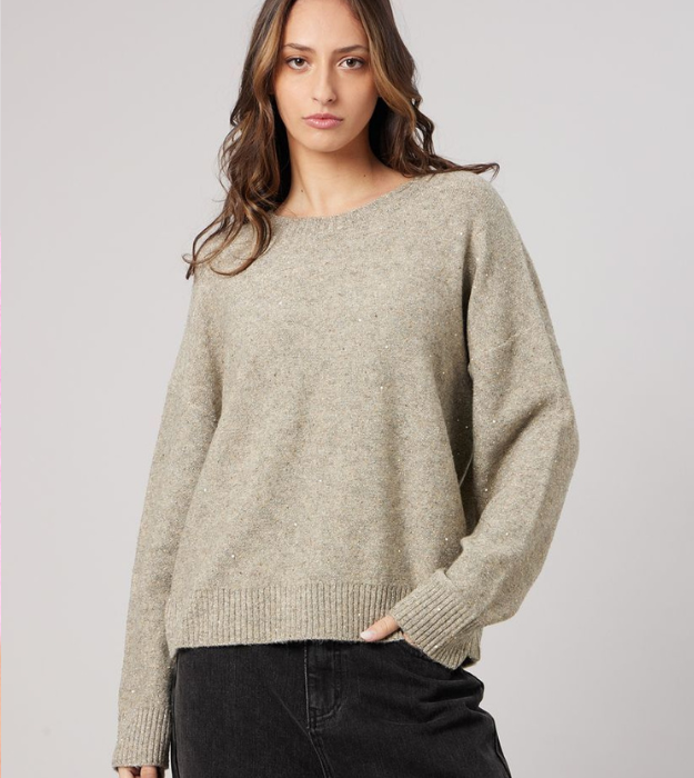 Femme portant un pull beige en maille à col rond et manches longues