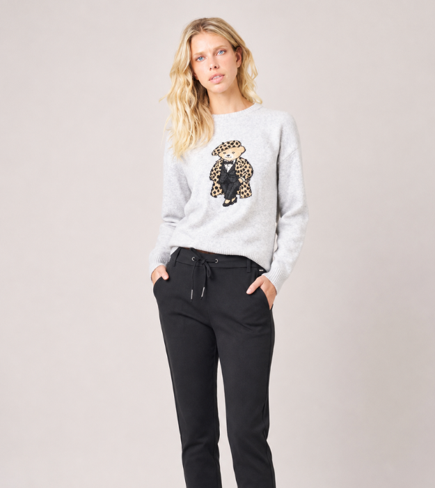 Femme portant un pull gris à motif ourson avec un pantalon noir